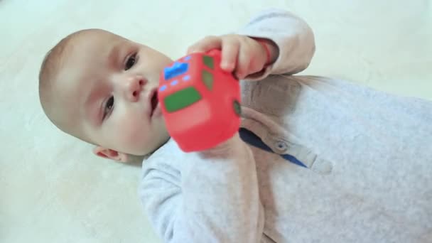 Niño está acostado sobre su espalda con un juguete — Vídeo de stock