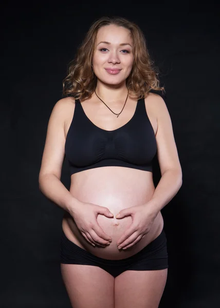 Fotografování těhotná žena v ateliéru v různých polohách — Stock fotografie