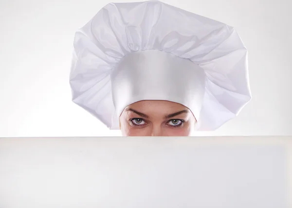 La donna bionda con i capelli corti in un cappello e cucinare con un bel sorriso tenendo un cartellone bianco — Foto Stock