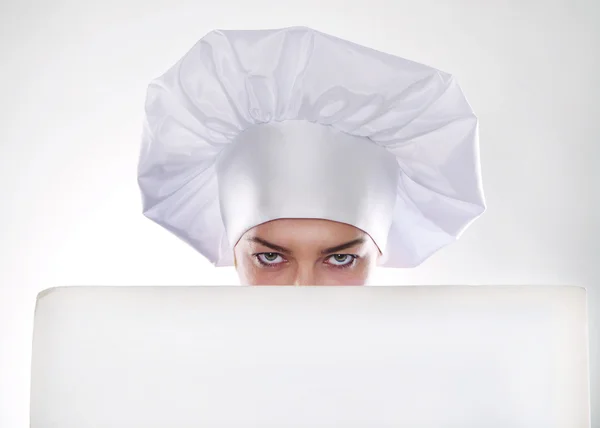 La donna bionda con i capelli corti in un cappello e cucinare con un bel sorriso tenendo un cartellone bianco — Foto Stock