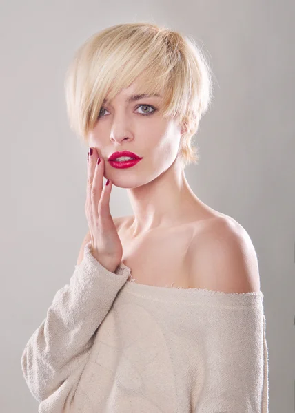 The blond woman with short hair and a beautiful smile with red lips isolated. Touches the lips — Stock Photo, Image