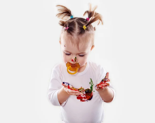 The baby girl with a pacifier in gouache soiled hands and shirt isolated — Stock Photo, Image