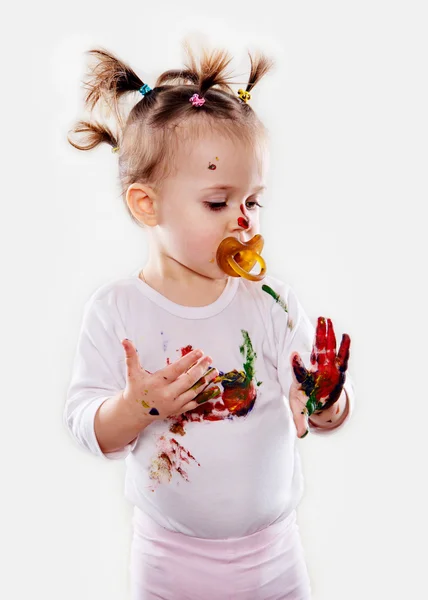 La niña con un chupete en gouache manos sucias y camisa aislada —  Fotos de Stock