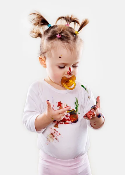 La niña con un chupete en gouache manos sucias y camisa aislada —  Fotos de Stock