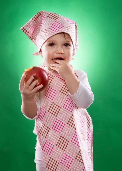 Το μωρό κορίτσι με ένα μαντήλι και κουζίνα ποδιά κρατώντας ένα λαχανικό που απομονώνονται — Φωτογραφία Αρχείου