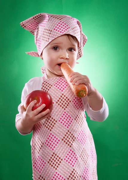 The baby girl with a kerchief and kitchen apron holding an vegetable isolated — Stock Photo, Image