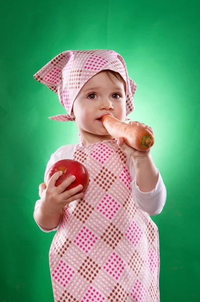 The baby girl with a kerchief and kitchen apron holding an vegetable isolated — Stock Photo, Image