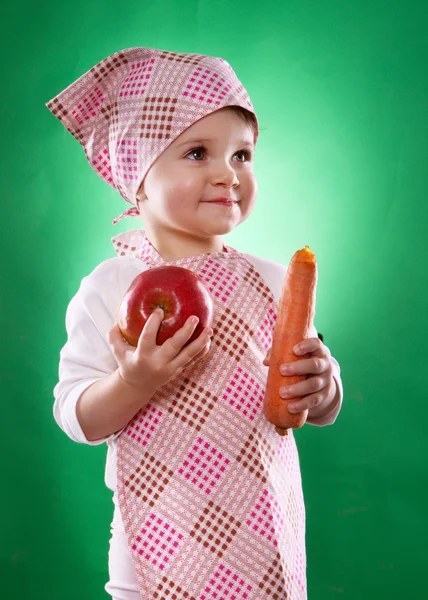 The baby girl with a kerchief and kitchen apron holding an vegetable isolated — Stock Photo, Image