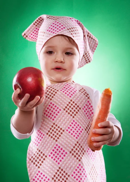 The baby girl with a kerchief and kitchen apron holding an vegetable isolated — Stock Photo, Image