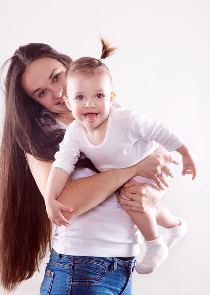 La joven madre con el pelo castaño largo en jeans sosteniendo a un bebé aislado — Foto de Stock