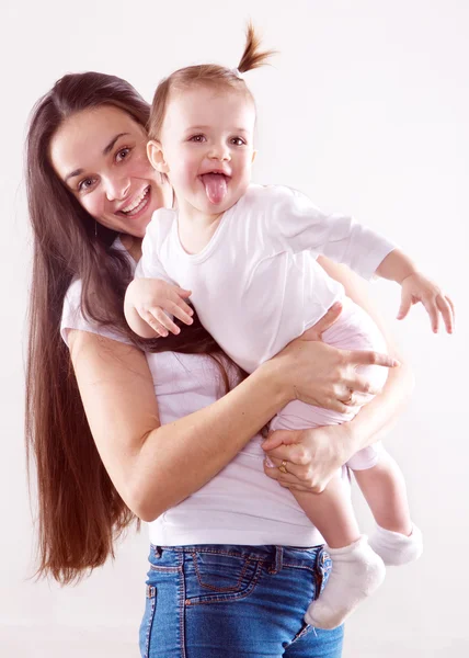 Die junge Mutter mit langen braunen Haaren in Jeans hält ein Baby isoliert — Stockfoto
