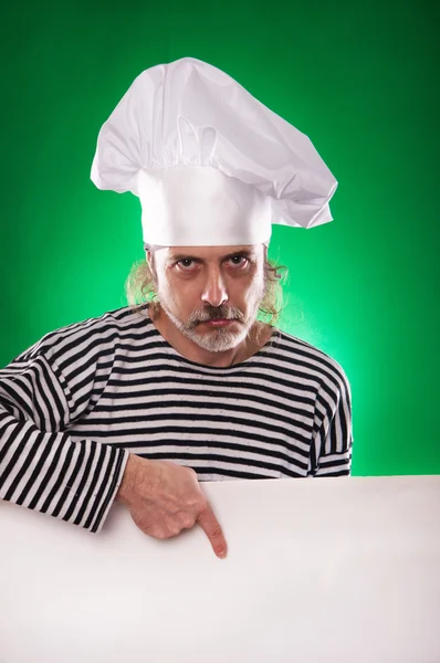 Muž s šedou bradkou v sailor oblek a klobouk kuchař ukazuje prstem na billboard, izolované — Stock fotografie