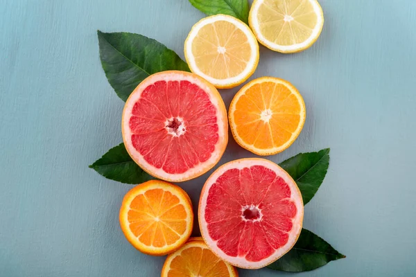 色彩艳丽的果片顶部 有柑橘叶缘排列 夏季热带果汁概念与柠檬 柚子和橙子在古老的蓝色桌子上 平躺在床上新鲜冰沙饮料菜单背景 — 图库照片