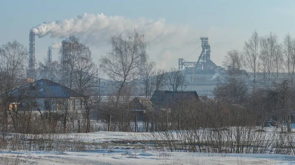 village house in winter on the background of an industrial factory.