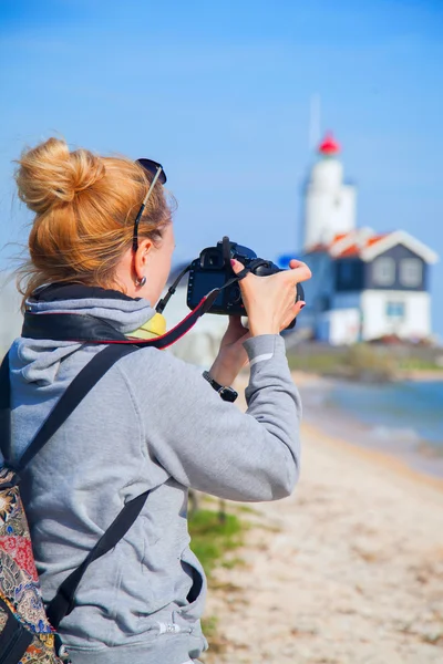 Girl shoots video at the lighthouse on the sea