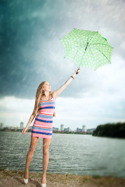 girl under an umbrella walks in the rain