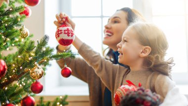 Mutlu Noeller ve mutlu tatiller! Anne ve kızı kapalı alanda ağacın yanında. Noel 'den önceki sabah. Portre seven aile. Yakın çekim.. 