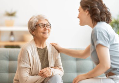 Güzel anne ve kız evdeki kanepede otururken konuşuyor ve gülümsüyor..