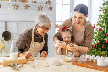 Mutlu Noeller ve mutlu tatiller. Aile hazırlığı bayram yemeği. Büyükanne, anne ve kızı kurabiye pişiriyor..