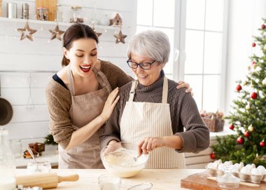Mutlu Noeller ve mutlu tatiller. Aile hazırlığı bayram yemeği. Anne ve kızı zencefilli ekmek evi pişiriyor..