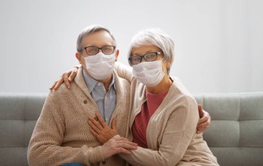 Coronavirus ve grip salgını sırasında maske takan yaşlı bir çift. Virüs ve hastalık koruması, ev karantinası. COVID-2019. Maskeleri çıkarmak ya da çıkarmak.