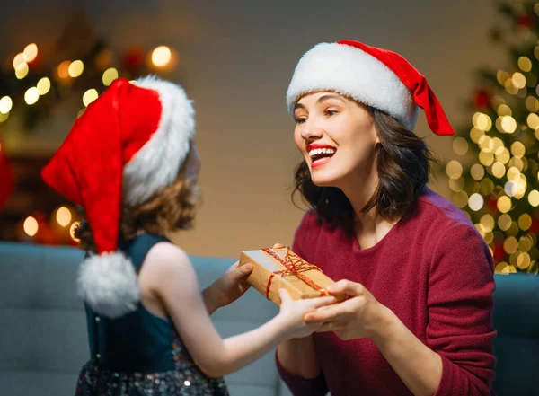 メリークリスマスとハッピーホリデー 陽気な母親とかわいい娘の女の子は贈り物を交換します 屋内で木の近くで遊んでいる親と小さな子供 プレゼント付きの家族を愛する — ストック写真