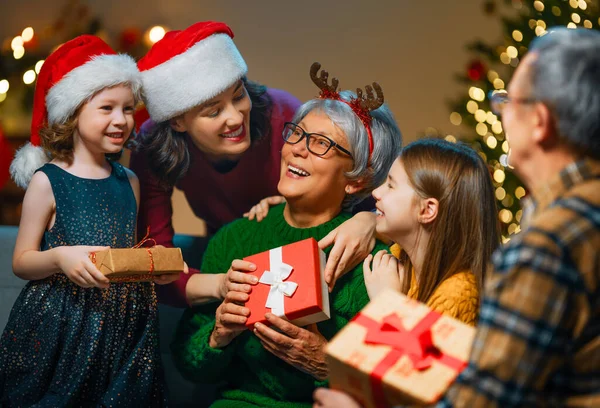 メリークリスマスとハッピーホリデー おばあちゃん おじいちゃん お母さん 子供たちが贈り物を交換します 屋内で木の近くで遊んでいる両親と娘 プレゼント付きの家族を愛する — ストック写真