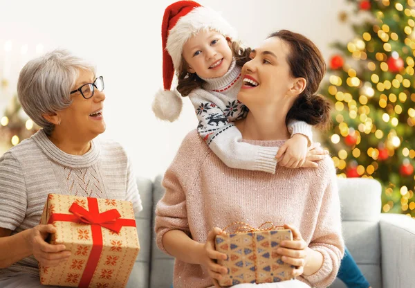 メリークリスマスとハッピーホリデー ママとおばあちゃんへの贈り物を提示する陽気な子供 屋内で木の近くで遊んでいる親と小さな子供 プレゼント付きの家族を愛する — ストック写真
