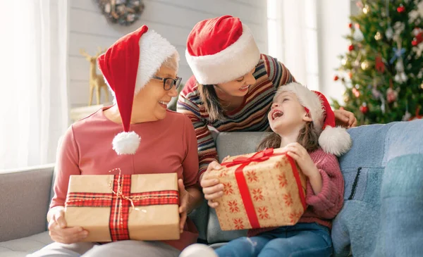 圣诞快乐 节日快乐 快乐的孩子送给妈妈和奶奶礼物 父母和小孩在室内树上玩得很开心 有礼物在房间里的爱的家庭 — 图库照片