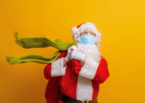 Merry Christmas and Happy Holidays! Santa Claus in face mask on bright color background. Covid-2019