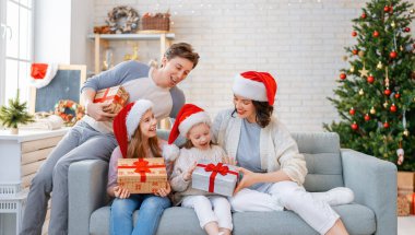 Mutlu Noeller! Güzel genç anne, baba ve kızları Noel ağacının yanında hediyelerle. 