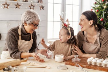 Mutlu Noeller ve mutlu tatiller. Aile hazırlığı bayram yemeği. Büyükanne, anne ve kızı kurabiye pişiriyor..