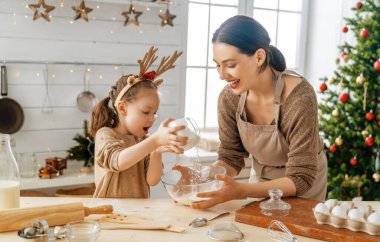 Mutlu Noeller ve mutlu tatiller. Aile hazırlığı bayram yemeği. Anne ve kızı kurabiye pişiriyor..