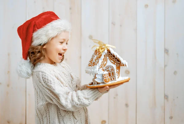 Szczęśliwa Dziewczynka Christmas Gingerbread House Białym Drewnianym Tle — Zdjęcie stockowe
