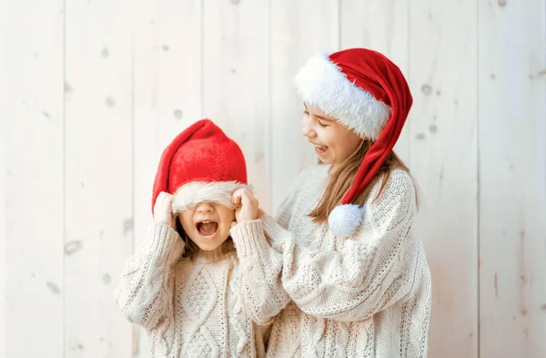 Glückliche Kleine Mädchen Mit Nikolausmützen Auf Weißem Holzgrund Weihnachtszeit — Stockfoto