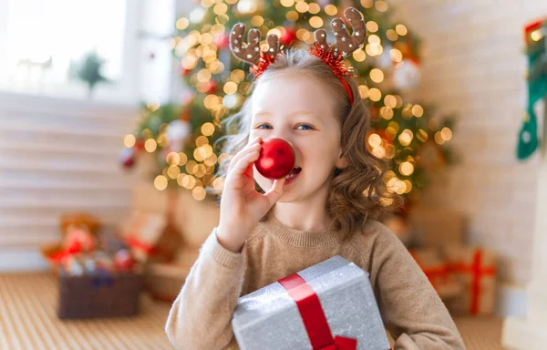 メリークリスマスとハッピーホリデー ギフト付きの陽気なかわいい子供の女の子 子供は木の近くで楽しんでいる — ストック写真
