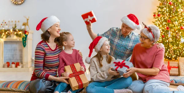 メリークリスマスとハッピーホリデー おばあちゃん お父さん お母さん 子供たちが贈り物を交換する 屋内で木の近くで遊んでいる両親と娘 プレゼント付きの家族を愛する — ストック写真