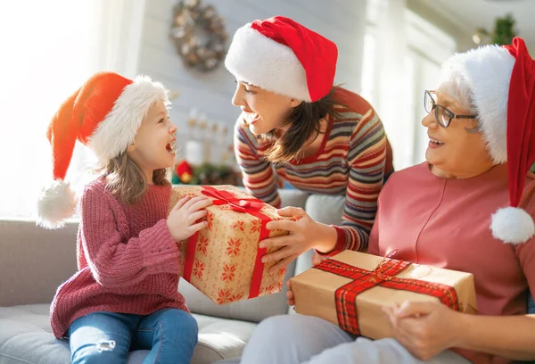 メリークリスマスとハッピーホリデー ママとおばあちゃんへの贈り物を提示する陽気な子供 屋内で木の近くで遊んでいる親と小さな子供 プレゼント付きの家族を愛する — ストック写真