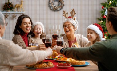Mutlu Noeller! Mutlu aile evde yemek yiyor. Kutlama tatili ve ağacın yakınındaki birliktelik.