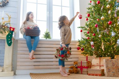 Mutlu Noeller ve mutlu tatiller! Pencerenin önünde oturan neşeli, sevimli çocuklar. Çocuklar sabah ağaçların yanında eğleniyorlar..