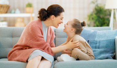 Evde iyi vakit geçirin. Anne ve kızı oynuyorlar, gülümsüyorlar ve sarılıyorlar. Aile tatili ve birliktelik. 