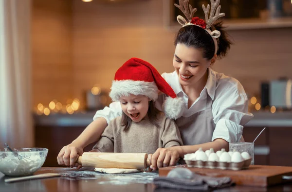 Merry Christmas and Happy Holidays. Family preparation holiday food. Mother and daughter cooking cookies.