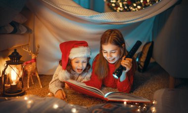 Mutlu Noeller! Güzel kız kardeşler Noel ağacının yanında kitap okuyor.. 