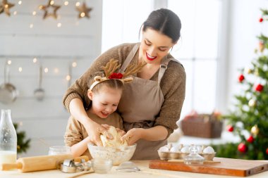 Mutlu Noeller ve mutlu tatiller. Aile hazırlığı bayram yemeği. Anne ve kızı kurabiye pişiriyor..