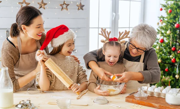 Merry Christmas and Happy Holidays. Family preparation holiday food. Grandma, mother and daughters cooking cookies.