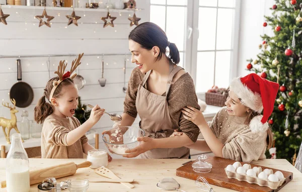 Merry Christmas and Happy Holidays. Family preparation holiday food. Mother and daughters cooking cookies.