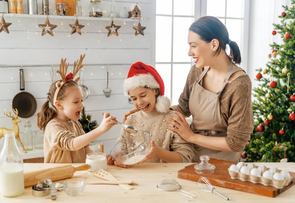 Merry Christmas and Happy Holidays. Family preparation holiday food. Mother and daughters cooking cookies.