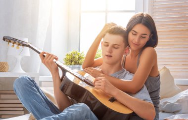 Aşık mutlu bir çift. Genç şık moda çiftimizin göz kamaştırıcı şehvetli portresi. Genç adam sevgili kızı için gitar çalıyor..
