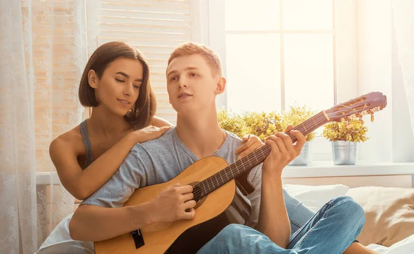 愛の幸せなカップル 室内で若いスタイリッシュなファッションカップルの見事な官能的な肖像画 若いです男遊びギターのために彼の最愛の女の子 — ストック写真