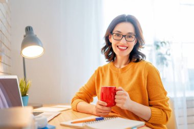 İnternette ders çalışan, Webinar izleyen, dizüstü bilgisayarda podcast yapan notlar alan, çalışma masasında oturan genç bir iş kadını. E-öğrenme kavramı.